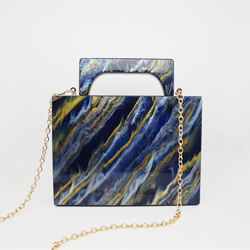 Bolso de noche acrílico con polvo dorado y pintura azul perlado.